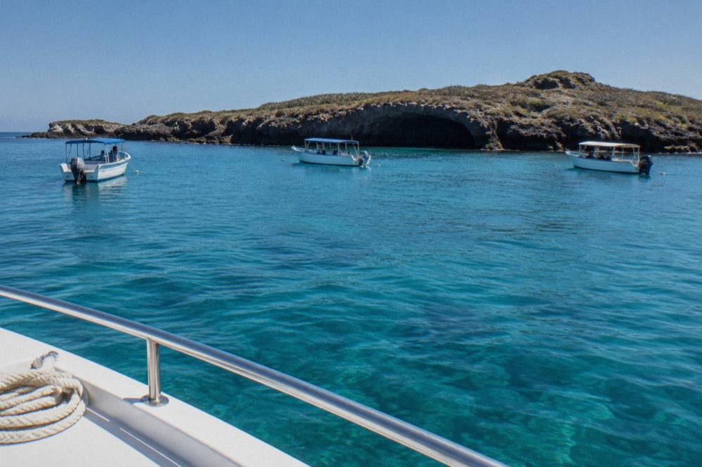 Tour boats anchored near the cliffs of the Marietas Islands on clear water
